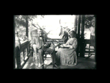 Jackson Taylor and Martha Nuttall Taylor on porch at Swarthmore, PA. Both are seated, he in a wicker rocking chair.