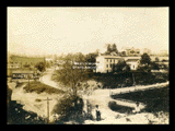 View of Lumberport. Two children in foreground. Signs include Sun Brothers Worlds Progressive Shows, Delaval Separators.